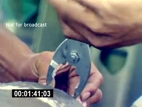 The still from the 'USMC Aviation Ordnance Recruiting Film - Silent' features a close-up of hands using a pair of pliers. The focus is on the precision and skill involved in handling ordnance materials. The background suggests an aviation setting, likely emphasizing the technical aspects of Marine Corps aviation ordnance work. The timestamp indicates the moment in the film sequence.