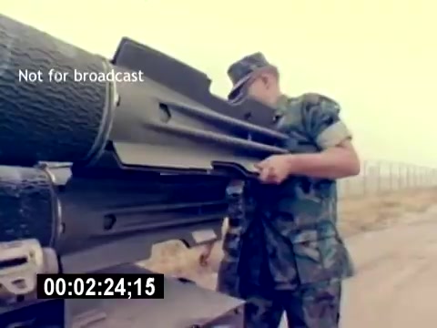 The still from the 'USMC Aviation Ordnance Recruiting Film - Silent' shows a service member in military camouflage working on a large piece of ordnance equipment. The setting appears to be outdoors, with a blurred background that suggests a military installation or training area. The soldier is inspecting or handling the equipment, which indicates a focus on aviation ordnance responsibilities within the USMC. The overall tone conveys a sense of duty and technical skill.