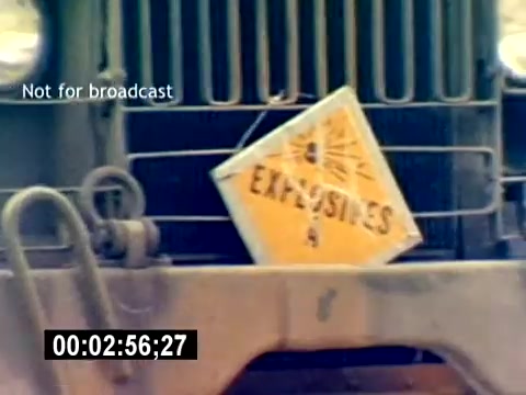 The still features a military vehicle with a clear warning sign labeled 'EXPLOSIVES' prominently displayed. The vehicle appears rugged, likely indicating its use in a combat or operational setting. The context suggests it is part of a USMC (United States Marine Corps) Aviation Ordnance recruiting film, emphasizing the importance of handling explosives and ordnance in aviation operations. The timestamp indicates it's a brief moment within the film, conveying a serious and cautionary theme.
