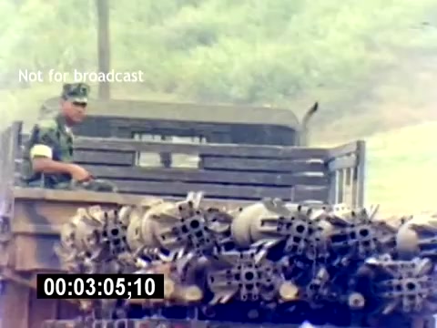 The still from the 'USMC Aviation Ordnance Recruiting Film - Silent' shows a U.S. Marine standing on the back of a military truck. The truck is loaded with ordnance, including various types of munitions. The environment appears rugged, suggesting a training or operational setting. The image captures the military atmosphere but lacks any accompanying sound.