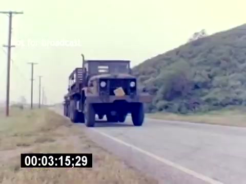 The still depicts a military truck driving along a rural road, surrounded by grassy fields and telephone poles. The landscape features rolling hills in the background. The image appears to capture a moment from the 'USMC Aviation Ordnance Recruiting Film,' highlighting transportation or logistics related to marine aviation ordnance. The timestamp at the bottom indicates 3 minutes and 15 seconds into the film.