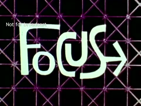 The still features the word 'FOCUS' displayed in a stylized, playful font, set against a geometric grid background. The lively colors and design emphasize a modern, technology-driven theme, aligning with the educational context of IBM's computer technology from 1963. The phrase suggests a concentration on enhancing educational processes through computing, including aspects like grades and course enrollment. The 'Not for broadcast' watermark indicates that this is a production still not intended for public airing.