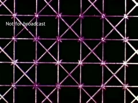 The still from 'IBM - The Information Center (1963)' features a grid pattern illuminated with intersecting lines and points, creating a visually dynamic representation of data processing. This imagery reflects IBM's early use of technology in educational settings, highlighting concepts like organization and information management through computing methods, including punch cards. The overall aesthetic suggests a blend of technology and educational infrastructure.