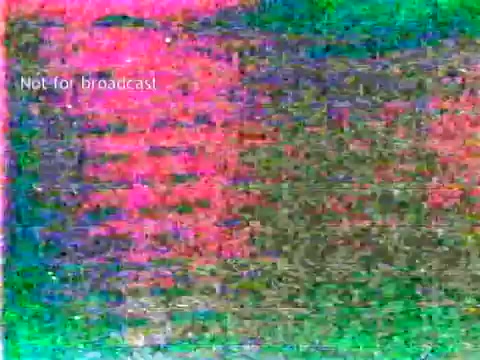 The still from 'IBM - The Information Center (1963)' likely features a visual representation of early computer technology, possibly showing the use of punch cards in educational settings. The film illustrates how IBM's technology can streamline processes like grade management and course enrollment. The vibrant, distorted colors in the still suggest a vintage film quality, typical of the era, and indicate that the footage may not be in pristine condition.