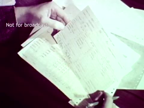 The still from 'IBM - The Information Center (1963)' shows hands holding multiple sheets of paper, likely containing course and grade data. The documents appear to be forms typical of the era, possibly punch cards or related materials, emphasizing IBM's role in streamlining administrative tasks in education. The caption 'Not for broadcast' indicates the context is restricted to educational or archival use.