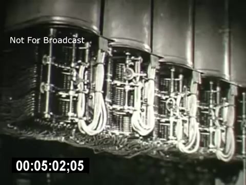 The still from 'Bell System - Story Without End' features a close-up of intricate telecommunications equipment, showcasing various metal components and wiring. The focus on the machinery highlights the technological advancements in communication systems, emphasizing the complexity and engineering behind telecommunications. The visual context suggests a narrative around the evolution and significance of the Bell System.