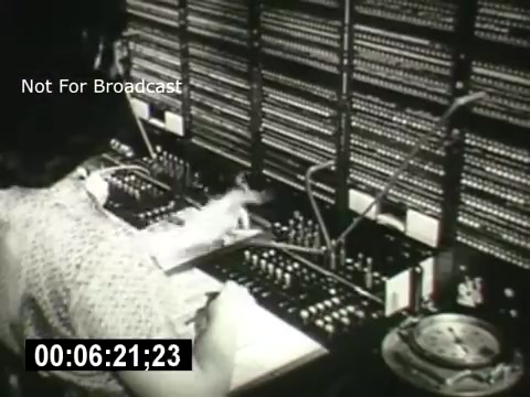 The still captures a scene from 'Bell System - Story Without End,' featuring an operator seated at an old-fashioned telephone switchboard. The operator is focused on their work, manipulating a series of plugs and wires, surrounded by a multitude of connection panels. The vintage equipment highlights the labor-intensive nature of telecommunications before modern technology. A timer in the corner suggests the moment is part of a timed segment. The text 'Not For Broadcast' indicates that the image is for private viewing or reference only.