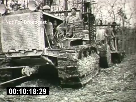 The still captures a scene from 'Bell System - Story Without End,' featuring a large caterpillar tractor in a wooded area. A man operates the tractor, while two others work nearby. The environment appears rugged and natural, typical of outdoor labor settings. The image conveys themes of progress and industry associated with the Bell System's narrative. The timestamp and 'Not For Broadcast' label indicate it is a protected still from the film.
