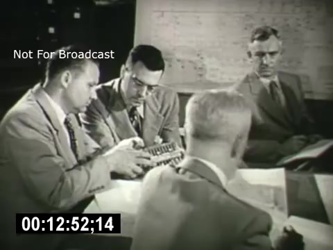 The still from 'Bell System - Story Without End' features a group of four men engaged in a discussion around a table. One man in the foreground is holding a small model or device, while the others appear to be examining documents and blueprints. The setting suggests a corporate or engineering environment, likely focused on telecommunications. The image is marked 'Not For Broadcast,' indicating its restricted use.