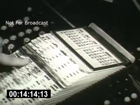 The still from 'Bell System - Story Without End' shows a close-up of a hand interacting with a card index system. The index appears to contain various cards with printed information, possibly related to telecommunications. The black-and-white image exemplifies the era's technology, emphasizing organization and data management within the Bell System.