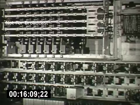The still from 'Bell System - Story Without End' depicts a complex array of telecommunications equipment, likely showcasing various switches and circuits. The overhead perspective emphasizes the intricate design and organization of the components, reflecting the technological advancements in communication systems of the time. The frame includes a timestamp and a 'Not For Broadcast' label, indicating it is meant for archival purposes.