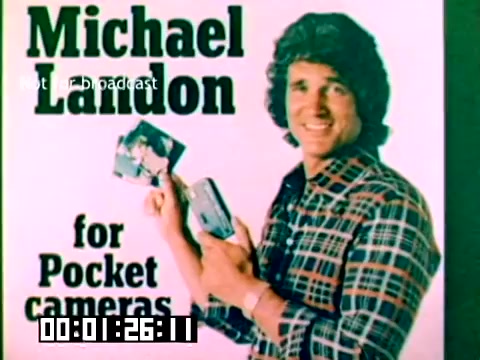 The still features Michael Landon promoting Kodak's pocket cameras. He is smiling and holding photographs, dressed in a plaid shirt. The background includes text that highlights his endorsement for Kodak products, suggesting a focus on accessible and personal photography. The image captures a vibrant and friendly atmosphere typical of promotional materials from the late 1970s.
