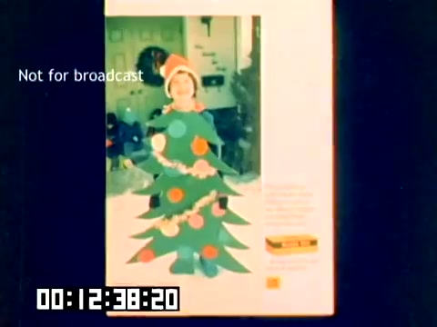 The still depicts a colorful promotional image from a Kodak sales film, showcasing a child dressed in a playful costume designed to resemble a Christmas tree. The child is adorned with ornaments and a festive hat, evoking a whimsical holiday spirit. The background is slightly blurred, suggesting a home setting, while a 'Not for broadcast' label indicates the film's private nature. The timestamp at the bottom provides a sequential mark within the film.