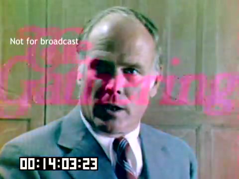 The still from the 16mm Kodak sales film features a man in a suit, likely addressing an audience. He has a serious expression, suggesting he is involved in a presentation or discussion. The background consists of wooden paneling, adding a classic feel to the scene. Superimposed text indicates 'Not for broadcast' and features a stylized title that includes 'The Gathering,' suggesting it might be part of a promotional or instructional context. The timestamp at the bottom indicates the specific moment within the film.