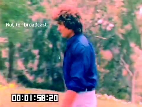 The still features a man, likely Michael Landon, walking through a vibrant outdoor setting filled with greenery. He is wearing a blue shirt and light pants, capturing a relaxed and casual atmosphere. The footage is marked as 'Not for broadcast,' and has a timestamp indicating its place within the film. The overall color palette appears soft and slightly faded, typical of vintage film.