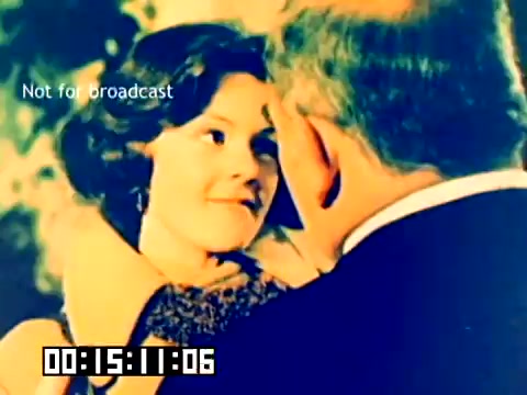 The still features a warm, nostalgic scene with a woman smiling tenderly as she interacts closely with a man. The colors are vibrant yet slightly faded, typical of the era's film stock. The framing suggests an intimate moment, possibly a romantic exchange or a heartfelt conversation. Overlaid text indicates 'Not for broadcast,' and there is a timecode at the bottom, marking the film's duration. This segment reflects the sentimental tone often found in promotional material from the late 1970s.