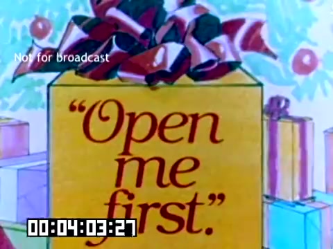The still features a brightly colored, illustrated gift box adorned with a large ribbon. The box has the phrase 'Open me first.' prominently displayed in bold lettering. In the background, there are several other wrapped presents, contributing to a festive atmosphere. The scene likely emphasizes the excitement of gift-giving, aligning with Kodak's promotional theme. A timestamp indicating 4 minutes and 3 seconds is displayed at the bottom, along with a 'Not for broadcast' label.