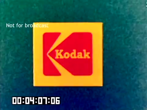 The still features the iconic Kodak logo prominently displayed against a teal background. The logo consists of a yellow square with a red border and a stylized yellow 'K,' conveying a classic retro design. In the lower left corner, there is a timestamp indicating the film's progress at 4 minutes and 7 seconds. The text 'Not for broadcast' is visible, highlighting the film's intended use as a private sales tool rather than for public airing. The overall aesthetic reflects the design sensibilities of the late 1970s.