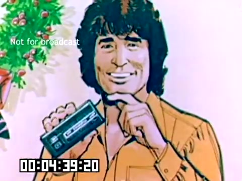 The still features a smiling man with curly hair, holding a Kodak camera, set against a background that includes Christmas decorations. It's a promotional image from a silent Kodak sales film from 1977, showcasing the camera in a cheerful context. The timestamp at the bottom indicates the duration, and there's a 'Not for broadcast' watermark present.