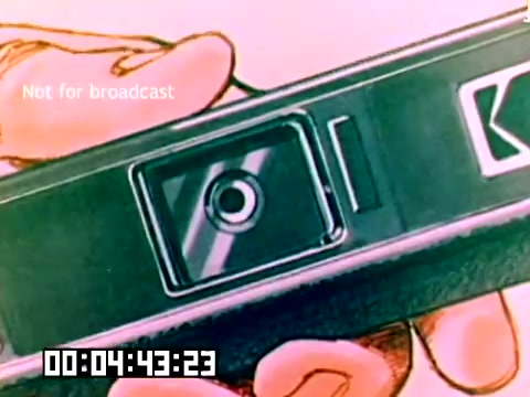 The still captures a hand holding a Kodak camera, prominently featuring the lens and shutter mechanism. The camera appears to be a typical model from the late 1970s, characterized by its simple design and branding. The image has a colorful, slightly animated quality, suggesting it may have been part of a promotional or instructional piece. The overlay text indicates it is not for broadcast, and a timer shows the elapsed footage. Overall, the still emphasizes Kodak's product as engaging and user-friendly.