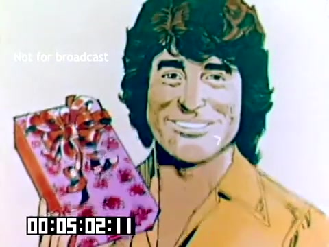 The still shows a stylized illustration of Michael Landon smiling and holding a gift-wrapped present. He has curly hair and is wearing a light-colored shirt. The background features bright colors, typical of promotional materials from the 1970s. There's a timecode at the bottom left and a watermark stating 'Not for broadcast.' The promotional context suggests a focus on photography or family moments tied to Kodak's products.