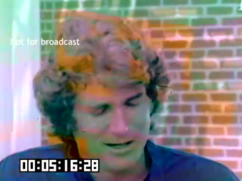 The still features a young man, likely Michael Landon, with a wavy hairstyle, looking thoughtfully downward. The background consists of a patterned wall, possibly brick, and the image has a surreal color distortion. A timecode at the bottom indicates the frame's position in the film. The overlay reads 'Not for broadcast,' indicating it's a private or promotional clip. Overall, it captures a casual moment from a sales presentation, despite the absence of sound and context.