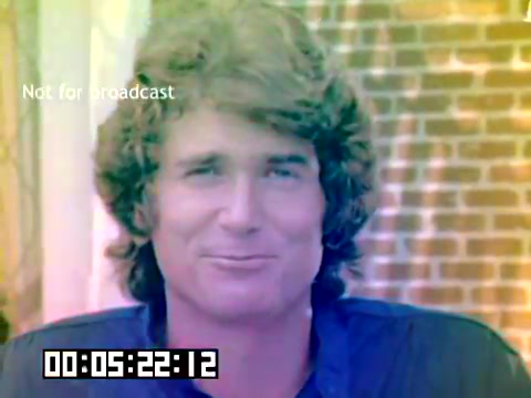 The still from the Kodak sales film features a man with curly hair and a relaxed expression, likely Michael Landon. He is framed against a backdrop that suggests a casual setting, possibly outdoors. The image has a vintage quality typical of 1970s films and includes timecode information at the bottom, indicating that it is a recorded segment. The overall tone conveys a friendly and approachable demeanor, characteristic of the era's media style.