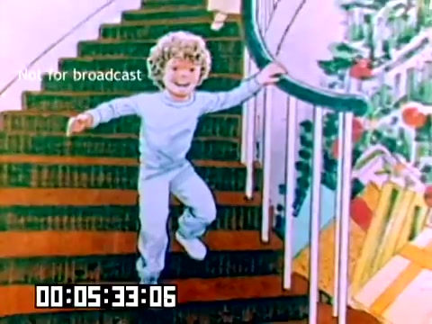 The still features a child with curly hair joyfully descending a staircase. The decorative steps are adorned with festive elements, suggesting a cheerful atmosphere. The surrounding environment hints at a holiday or celebratory context, with colorful decorations visible. The frame has a timecode and a watermark indicating that it is not for broadcast. Overall, the image conveys a sense of joy and nostalgia typical of family-oriented marketing from the late 1970s.