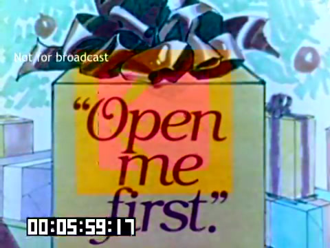 The still features a decorated gift box adorned with a bow and the phrase “Open me first” prominently displayed on its surface. The background includes hints of holiday-themed decorations, suggesting a festive atmosphere. The visual presents a cheerful invitation to engage with the gift, characteristic of promotional advertising in the 1970s. The timestamp at the bottom indicates a running time of 5 minutes and 59 seconds.