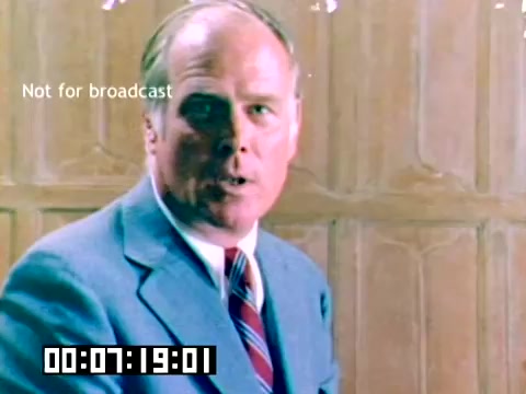 The still shows a man, dressed in a light blue suit with a red and blue striped tie, speaking directly to the camera. He appears to be in a professional setting, possibly a promotional or sales environment. A wood-paneled backdrop is visible, suggesting a formal atmosphere. The image is marked 'Not for broadcast' and includes a timecode at the bottom. The overall tone suggests a corporate or informative presentation related to Kodak products from 1977.