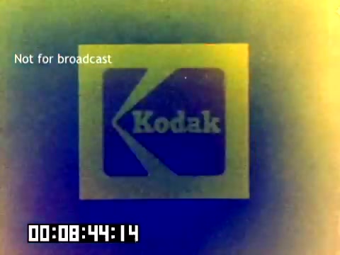 The still features a colorful, retro logo of Kodak, prominently displayed in the center. The logo is framed by a gradient of colors, creating an eye-catching effect reminiscent of 1970s aesthetics. The text 'Not for broadcast' is shown in the upper left corner, and a time code appears at the bottom, indicating the timing of the footage. The overall appearance is characteristic of vintage film, with slight grain and a faded quality.