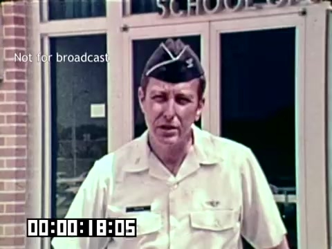 The still features a military officer standing in front of a building labeled 'School of...' possibly indicating a training or educational facility. He is wearing a military uniform and cap, suggesting a serious tone. The context of the image relates to an Air Force newsfilm focused on combating gangrene and emphasizing the importance of medical practices to save lives. A timestamp at the bottom indicates the film's duration, suggesting it's part of a larger presentation.