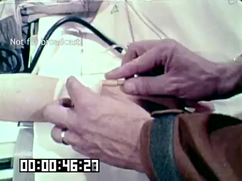 The still from the Air Force newsfilm 'Stopping gangrene - saving lives' shows a close-up of a person's hand applying a medical device on a patient's arm. The focus appears to be on a technique or treatment relevant to preventing gangrene, emphasizing the hands-on, clinical aspect of medical intervention. The context suggests a demonstration of important medical practices in a military or emergency setting.