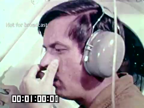 The still from the Air Force newsfilm 'Stopping gangrene - saving lives' features a male individual wearing large headphones. He appears to be engaged in some activity, potentially involved in medical protocols, given the film's focus on preventing gangrene and saving lives. The image captures an important moment related to military medical practices, emphasizing the urgency and seriousness of healthcare in a military context.
