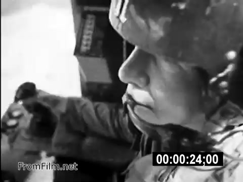 This 16mm still from 'Your Man In Vietnam' depicts Specialist 6 James Daly, a flight engineer for the CH-54 helicopter. The image captures Daly in a moment of focus, likely during a flight operation, showcasing the serious and composed demeanor characteristic of military service members during the Vietnam War. The context highlights the realities faced by those in the army, emphasizing their roles and responsibilities in the challenging environment of the conflict. This PSA aims to inform and recruit, reflecting the era's military strategy and public engagement efforts.