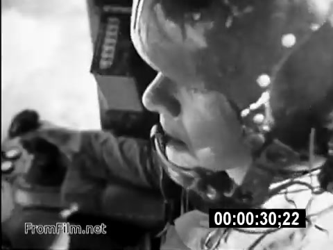 The still from the PSA 'Your Man In Vietnam' features Specialist 6 James Daly, a CH-54 flight engineer, in a close-up shot. The image captures him focused and engaged, likely in a cockpit environment, emphasizing the technical and demanding nature of his role. The backdrop suggests a military setting, representative of the Vietnam War era, illustrating the brave contributions of American service members. The emotional weight of daily life in the army is palpable, reflecting both the tension and responsibility faced by soldiers during this tumultuous period.