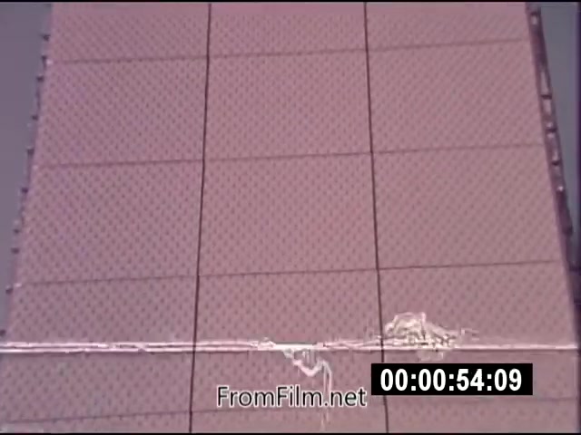 The 16mm still from 'Energy From Space,' part of NASA actuality footage from September 1976, depicts a close-up view of a surface with a grid-like pattern. The footage is silent and presents an experimental context, likely related to energy transmission concepts. The details in the film emphasize the technological aspects and visual aesthetics relevant to energy research during that era. The timestamp at 1:46 indicates it is part of a longer piece focusing on innovative energy sources from space.