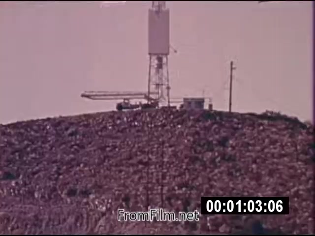 The still from 'Energy From Space,' a 16mm film from NASA dated September 1976, depicts a tall transmission tower atop a hill, surrounded by a landscape that appears to be littered with refuse or debris. The image is in color and has the characteristic appearance of archival footage from the 1970s. While the film's focus is on the concept of harnessing energy from space, the still captures a moment of the infrastructure involved in such energy transmission. The title suggests a focus on innovative energy solutions, potentially linking to advancements in space technology.