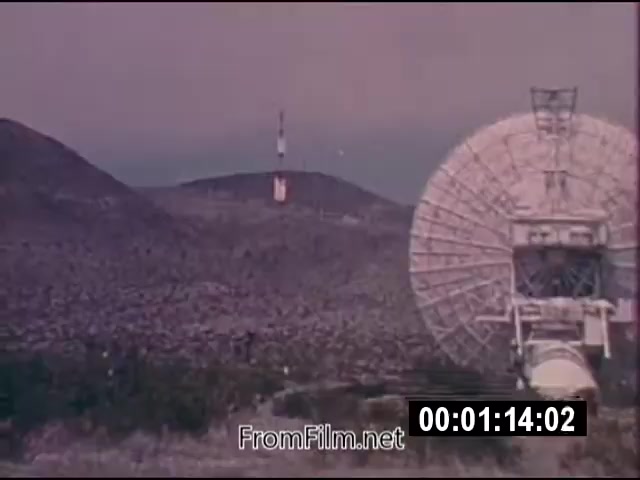 The 16mm still from 'Energy From Space' showcases a landscape featuring a large satellite dish in the foreground, aimed toward the sky. In the background, there are rolling hills with a communications tower visible, suggesting a setting focused on energy transmission or communication. The footage, dated September 1976, is silent and runs for 1 minute and 46 seconds. The overall aesthetic reflects the technological optimism of the era regarding harnessing energy from outer space.
