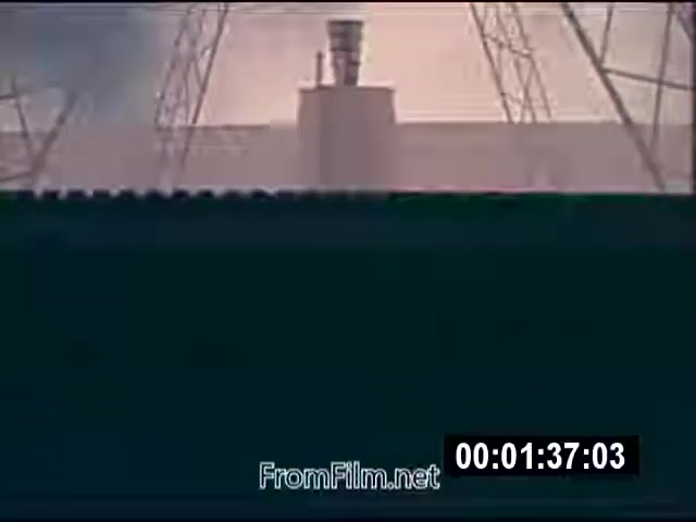 The still from 'Energy From Space' captures a moment in 16mm film, depicting a structure, likely a satellite or energy facility, under a cloudy sky. Tall towers or antennas surround it, suggesting a focus on technology related to energy transmission. The footage is from a NASA actuality film sent to a West Virginia TV station in September 1976, emphasizing space-based energy concepts. The film is silent and runs for 1 minute and 46 seconds.