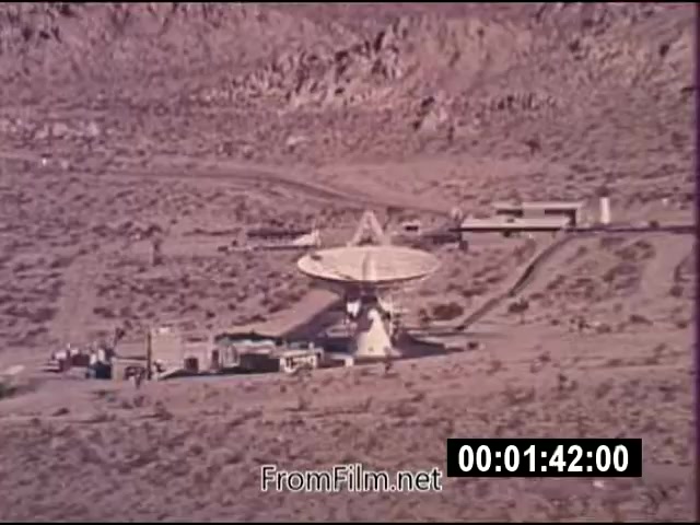 The still from 'Energy From Space,' a NASA actuality footage from September 1976, features the landscape showcasing a dish antenna setup, likely for satellite or energy transmission purposes. The scene captures a remote area with rocky terrain, surrounded by hills. The footage is silent and lasts 1 minute and 46 seconds. The film is noted for its color and presents actualities related to energy concepts explored during that era, reflecting NASA's research initiatives.