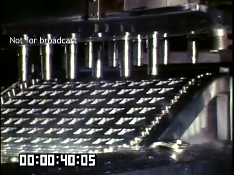 The still depicts a close-up of machinery involved in the production of frozen novelties. The equipment is likely a part of the freezing or molding process, showcasing metallic surfaces with a textured pattern. The lighting highlights the shiny, industrial nature of the machinery, typical of the 1950s-1960s film style. A timestamp indicates the duration of the footage, and a watermark states 'Not for broadcast.'