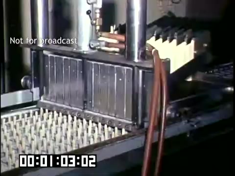 The still features a close-up view of machinery involved in the production of frozen novelties at DCA Food Industries. It showcases metal molds with small cavities, likely for shaping ice cream or similar treats, and attached hoses indicating the flow of ingredients. The Ektachrome footage captures the industrial process vividly, reflecting the technological era of the 1950s-1960s. The 'Not for broadcast' label suggests this was intended for internal use or archival purposes.