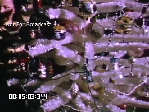 The still from 'In And Around Battle Creek Michigan' features a decorated Christmas tree, showcasing shiny ornaments and tinsel. The footage captures a festive atmosphere, with a close-up view emphasizing the colorful decorations. The scene appears to be warm and nostalgic, indicative of holiday celebrations.