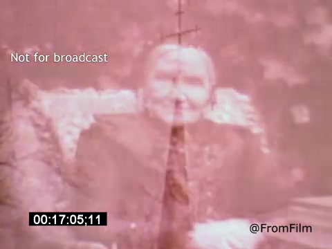 The still from 'Vincent Van Gogh: A Self-Portrait' (1961) features a muted, sepia-toned image that blends a portrait of an older individual with a faint backdrop. The subject appears to be smiling, seated comfortably in a decorative armchair, with soft floral patterns surrounding them. A vertical cross, likely from a window or structure, intersects the image, adding a layer of depth. The overall mood is reflective and poignant, capturing an essence of nostalgia.