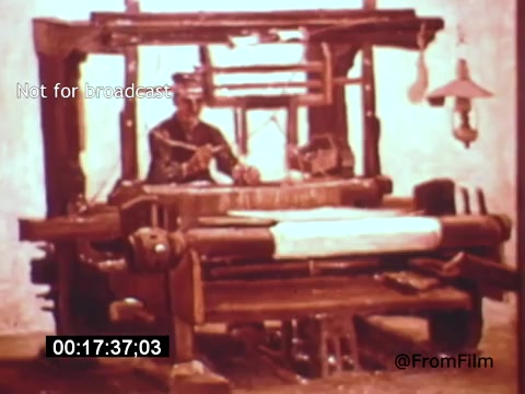 The 16mm still from 'Vincent Van Gogh: A Self-Portrait' (1961) features a scene with a figure working at a loom. The setting has a rustic, historical atmosphere, highlighted by earthy tones and a simple, unembellished backdrop. The figure appears focused on weaving, embodying the artistic and laborious spirit associated with Van Gogh's time. The overall composition reflects a blend of artistry and craftsmanship, showcasing the poignant connection to the creative process.
