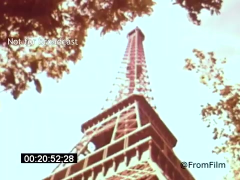 The still from *Vincent Van Gogh: A Self-Portrait (1961)* features a vibrant view of the Eiffel Tower, shot from a low angle. The structure is framed by lush foliage, creating a stark contrast between the architectural lines and the natural elements surrounding it. This iconic Parisian landmark signifies Van Gogh's connection to the city, reflecting the artistic atmosphere of his time. The film includes narration by Lee J. Cobb, enhancing the exploration of Van Gogh's life and artistry.