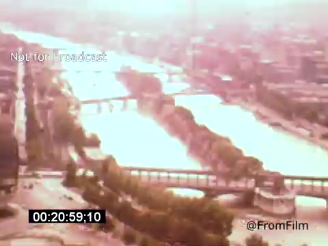 The still from 'Vincent Van Gogh: A Self-Portrait (1961)' appears to be a scenic aerial view of a river surrounded by urban landscapes. The image is infused with a warm, slightly sepia tone, suggesting a nostalgic atmosphere. The scene captures the flowing water and bridges, evoking a sense of tranquility amid the city backdrop. This visual context may reflect Van Gogh's emotional depth and connection to nature, as interpreted in the film narrated by Lee J. Cobb.
