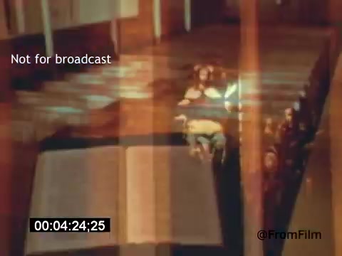 The still from 'Vincent Van Gogh: A Self-Portrait' (1961) features a dimly lit scene with an open book in the foreground, likely symbolizing Van Gogh’s reflections or thoughts. The background reveals impressions of figures, possibly suggesting a moment of introspection or solitude. The overall ambiance conveys a sense of contemplation, reflecting the complex emotions associated with Van Gogh's life and work. Lee J. Cobb provides narration, enhancing the film's exploration of the artist’s psyche.