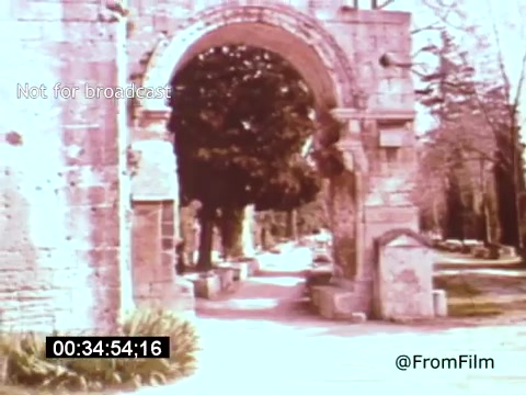 The still from 'Vincent Van Gogh: A Self-Portrait' (1961) features an archway in a serene, park-like setting. The stone structure is weathered and ornate, surrounded by lush greenery and trees, imparting a sense of history and tranquility. The image captures an artistic, reflective mood that complements the themes of the film.